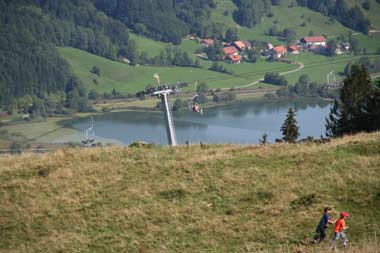 Doppelsesselbahn und Wanderer vor dem grossen Alpsee